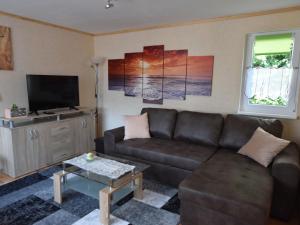 a living room with a brown couch and a tv at Pleasing Bungalow in Boiensdorf with Fenced Terrace in Boiensdorf