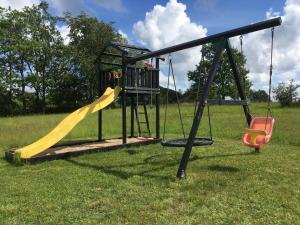 un parque infantil con tobogán y columpio en Jensens B&B en Egtved