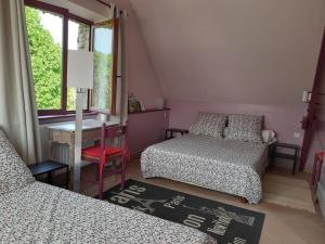 a bedroom with two beds and a desk and a window at La grange des lisières in Rouvres