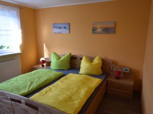 1 dormitorio con 2 camas con almohadas amarillas y verdes en Pleasing Bungalow in Boiensdorf with Fenced Terrace, en Boiensdorf