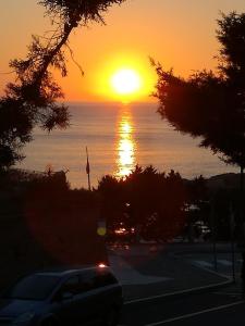 un tramonto sull'oceano con un'auto parcheggiata in un parcheggio di Le Rose Marine a Isola Rossa