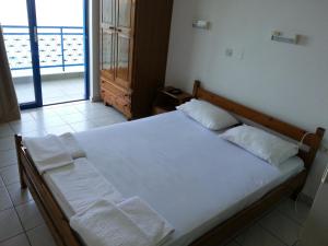 a bedroom with a large white bed with a window at Angelos Hotel in Agios Nikolaos