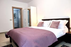 a bedroom with a large bed with a purple blanket at Sea Gem 2BR apt Spa n Pool Beach resort in Mamaia Nord