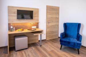 Cette chambre comprend un bureau et une chaise bleue. dans l'établissement Landgasthof-Hotel Zum Steverstrand, à Lüdinghausen