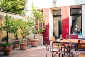 a patio with a table and chairs and trees at Maison de charme d'Arles in Arles