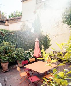 een tafel en stoelen met een roze parasol op een patio bij Maison de charme d'Arles in Arles