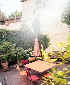 una mesa y sillas con una sombrilla rosa en el patio en Maison de charme d'Arles, en Arles