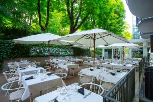 un restaurant avec des tables blanches et des parasols dans l'établissement Boutique Hotel Calzavecchio, à Casalecchio di Reno