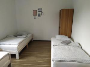 シュチェチンにあるMieszkanie pracownicze - 3 pokoje i parkingの白い壁とウッドフロアの客室で、ベッド2台が備わります。