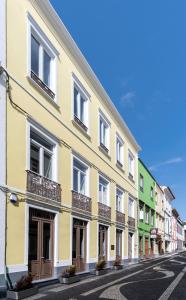 a yellow building with balconies on a street at Pé Direito in Ponta Delgada