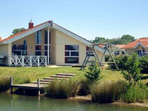 a house with a playground next to a lake at Four-Bedroom Holiday home in Otterndorf 5 in Otterndorf