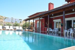 a swimming pool next to a building with white chairs at Ciftlik Hotel in Çeşme