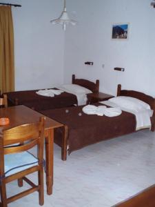two beds in a room with a table and a dining room at Mertonas Studios in Karpathos