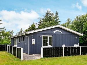 a blue building with a fence in front of it at Two-Bedroom Holiday home in Thyholm 4 in Sindrup