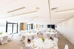 a large room with white tables and white chairs at Arche Hotel Lublin in Lublin