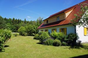 ein weißes Haus mit einem roten Dach und einem Hof in der Unterkunft Feriendorf am Bakenberg in Dranske