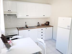 eine Küche mit weißen Schränken, einem Tisch und einem Waschbecken in der Unterkunft Damatria studio in Karpathos
