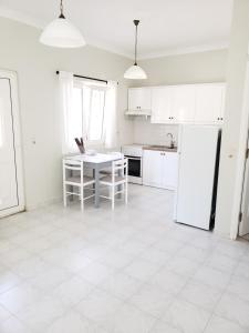 eine weiße Küche mit einem Tisch und einem Kühlschrank in der Unterkunft Damatria studio in Karpathos