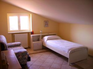 a bedroom with a bed and a window and a chair at Casetta dei "Prati" in Vaglio di Basilicata