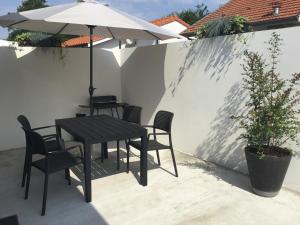 a table and chairs and an umbrella on a patio at Maison 47 m2 Biscarrosse proche lac et océan in Biscarrosse
