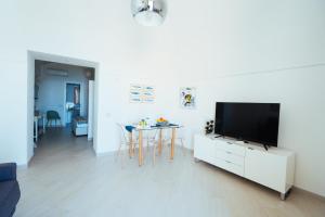 a white living room with a tv and a table at Chez Rosa - Cozy sea view openspace - 10mins from Belmond Caruso Ravello in Ravello +19 photos