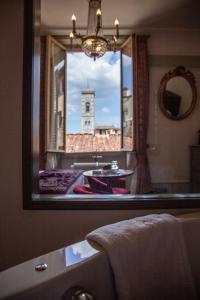 un bagno con specchio e vista su una torre dell'orologio. di Stanze del David Place a Firenze