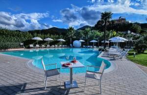 a pool with chairs and a table with a drink on it at San Severino Park Hotel & SPA, BW Signature Collection in Mercato San Severino
