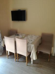 tavolo da pranzo con 2 sedie bianche e televisore di Feel Good Apartment a Mundanije