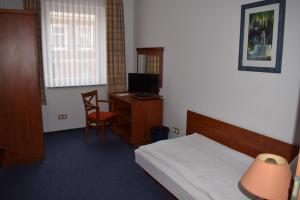 Schlafzimmer mit einem Bett und einem Schreibtisch mit einem TV in der Unterkunft Hotel garni "Am Hafen" in Havelberg