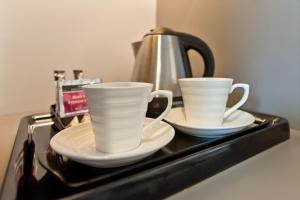 two cups and saucers on a tray with a tea kettle at Hotel Forza in Poznań