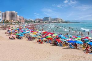 a crowd of people on a beach with umbrellas at Apartamento Pineda in Pineda de Mar