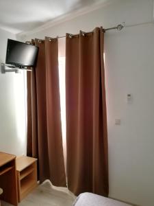 - une chambre avec un rideau brun et une télévision dans l'établissement Apartmani Roko, à Drvenik