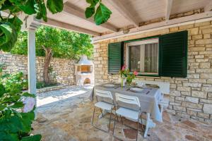 een patio met een tafel en stoelen aan een stenen muur bij Filomila House in Gaios