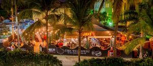 a group of people standing outside of a restaurant at night at Coconut Court Beach Hotel in Bridgetown