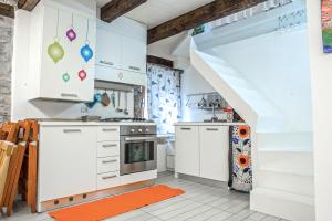 una cocina con armarios blancos y alfombra naranja en Tartana by KlabHouse, en Grado