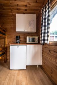 ブロメラにあるBromölla Camping o Vandrarhemの木造キャビンのキッチン(白い家電製品付)