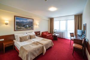 a hotel room with a large bed and a desk at Hotel Tatra in Zakopane