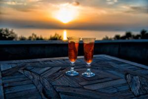 two glasses of beer sitting on a table with the sunset at Villa Rufola in Sorrento
