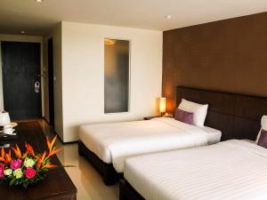 a hotel room with two beds and a table with flowers at Lub Sbuy House Hotel - SHA in Phuket Town +49 photos
