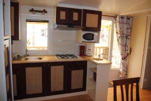 a small kitchen with a sink and a stove at MOBILHOME 3 CHAMBRES in Veyrignac +2 photos