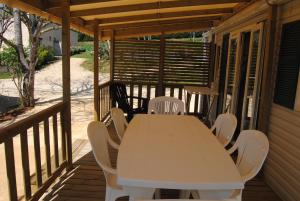a white table and chairs on a porch at MOBILHOME 3 CHAMBRES in Veyrignac