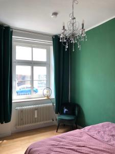 a bedroom with green walls and a bed and a chandelier at Luna Estela in Bayreuth