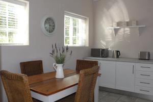 une cuisine avec une table et des chaises en bois dans l'établissement Kandelaars Cottage, à Oudtshoorn