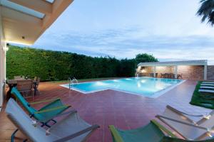 a swimming pool with chairs on a patio at Vila Nikopolis in Preveza