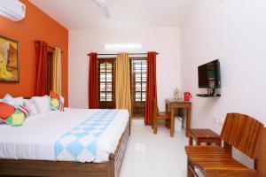Dormitorio con cama, escritorio y TV en Belhaven Home Stay en Thiruvananthapuram