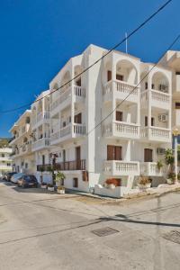 a white apartment building with white balconies on a street at Sea Stone Hotel in Karpathos
