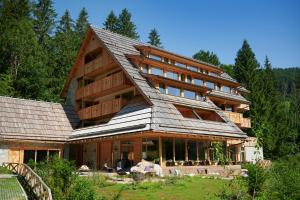 a large wooden house with a gambrel roof at Vila Planinka Boutique Hotel in Zgornje Jezersko