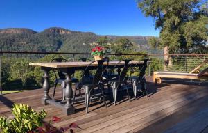 a table and chairs on a deck with mountains in the background at Amaroo Valley Springs in Barrengarry
