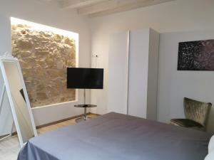 a bedroom with a bed and a tv on the wall at Judaica d'Ortigia in Syracuse