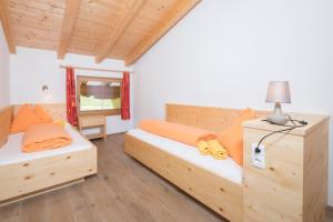 Habitación con 2 camas con almohadas de color naranja y lámpara. en Bauernhaus Roßmoos, en Alpbach